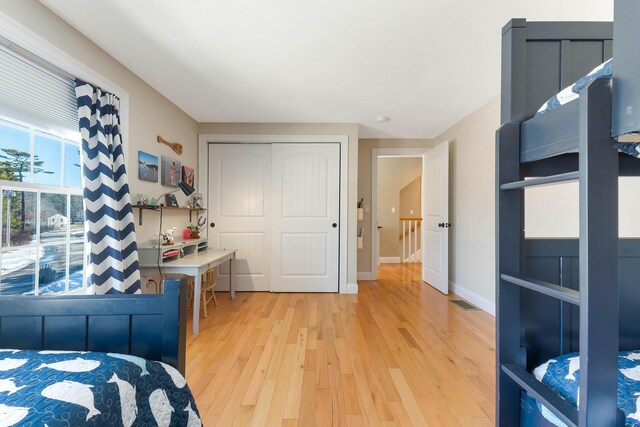 bedroom with light wood-style flooring, baseboards, and a closet