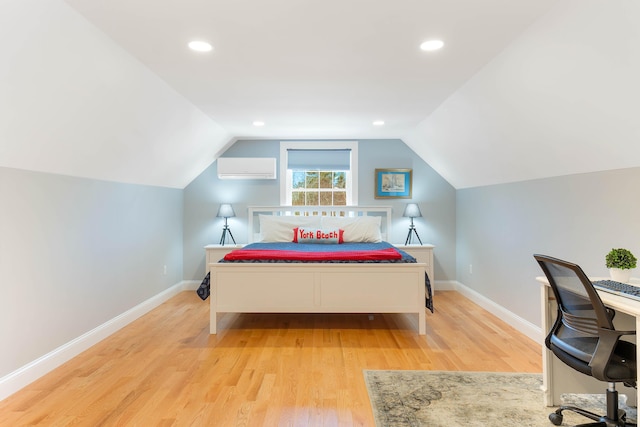 bedroom with an AC wall unit, baseboards, and wood finished floors