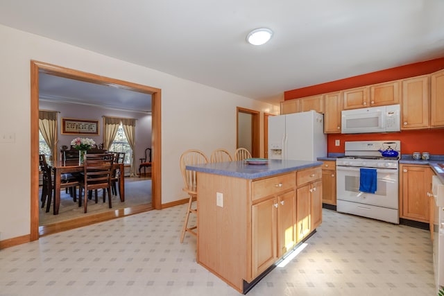 kitchen with a center island, light floors, dark countertops, white appliances, and baseboards