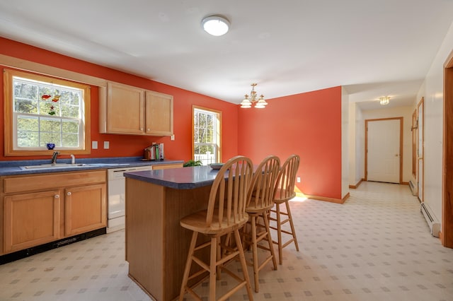 kitchen with a sink, light floors, dark countertops, and dishwasher