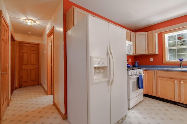 kitchen with white appliances, a sink, light brown cabinetry, light floors, and dark countertops