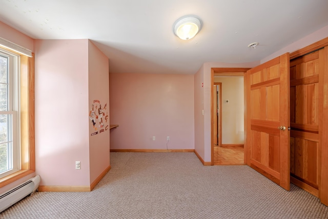 unfurnished room with a baseboard radiator, light colored carpet, and baseboards