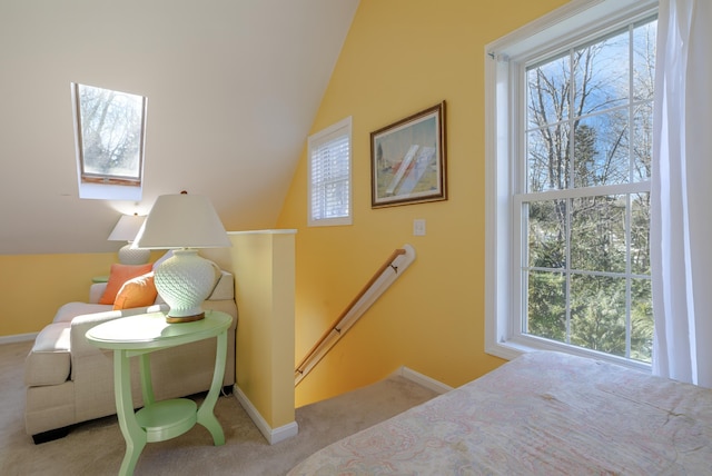 staircase featuring baseboards, carpet floors, lofted ceiling with skylight, and a healthy amount of sunlight