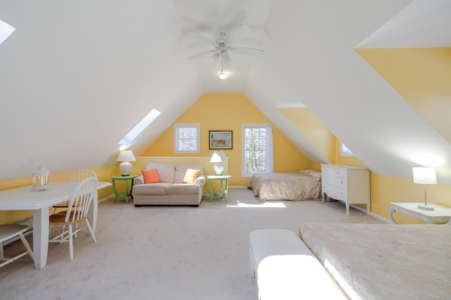 carpeted bedroom with lofted ceiling with skylight, baseboards, and a ceiling fan