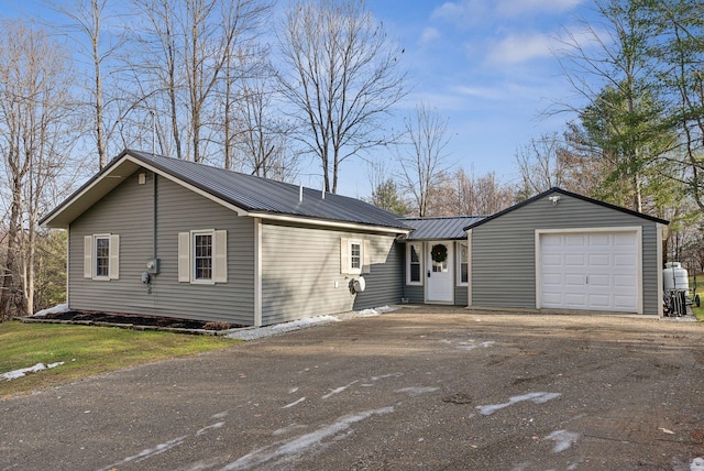 single story home featuring a garage, metal roof, and driveway