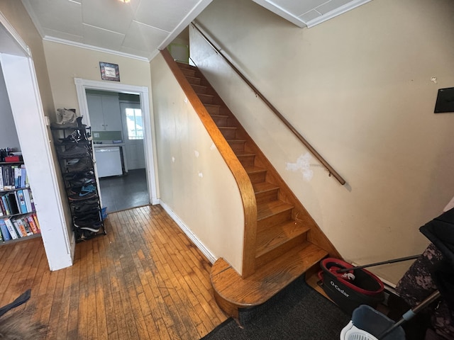 staircase with wood-type flooring and ornamental molding