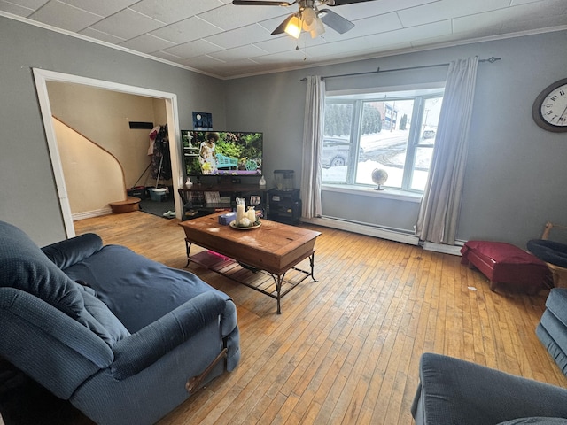 living room with a baseboard heating unit, crown molding, light wood finished floors, and a ceiling fan