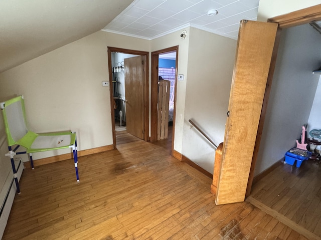 hallway with hardwood / wood-style flooring, baseboards, vaulted ceiling, and an upstairs landing