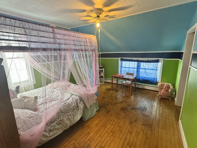 bedroom featuring hardwood / wood-style flooring, a baseboard heating unit, and a ceiling fan