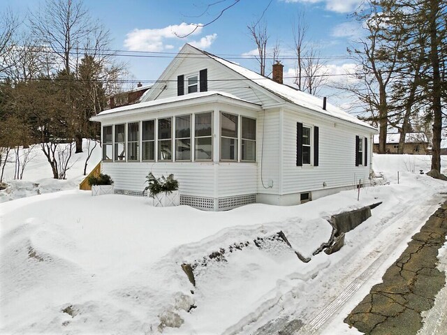 view of front facade featuring a sunroom and a chimney