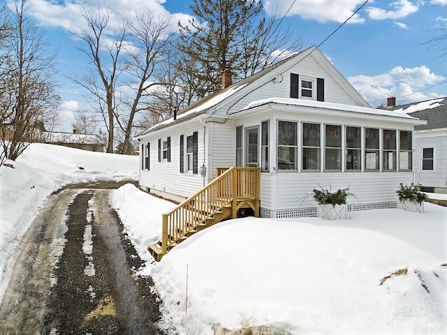 view of front facade featuring a sunroom and a chimney