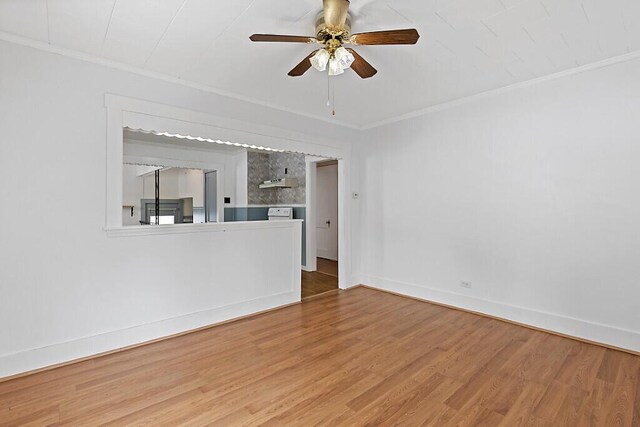 spare room with a ceiling fan, crown molding, baseboards, and wood finished floors