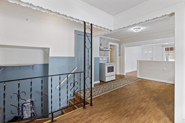 kitchen featuring electric stove, ornamental molding, wood finished floors, and under cabinet range hood