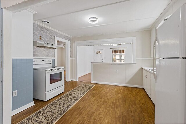 kitchen with white appliances, crown molding, under cabinet range hood, and wood finished floors