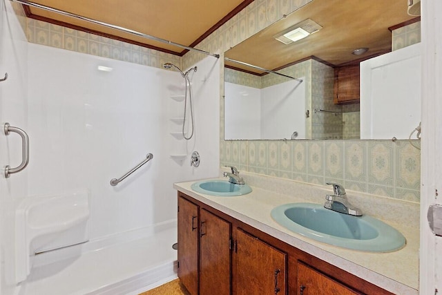 full bathroom with double vanity, curtained shower, a sink, and wallpapered walls