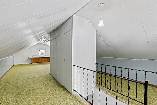 additional living space with wood walls, vaulted ceiling, and carpet flooring