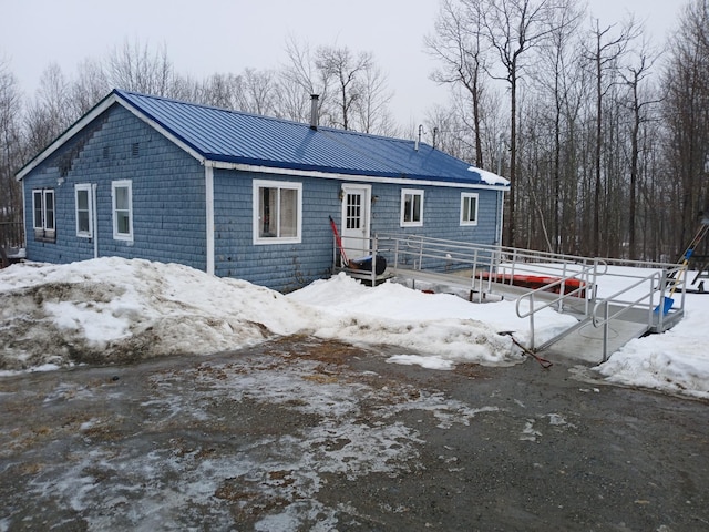 snow covered rear of property with metal roof