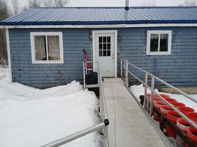 snow covered property entrance featuring metal roof