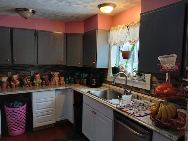 kitchen with tasteful backsplash, light countertops, a sink, a textured ceiling, and dishwasher