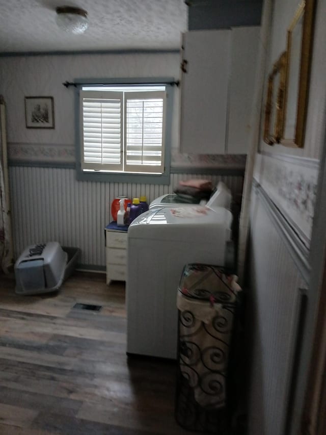 clothes washing area featuring washer / dryer, wainscoting, and wood finished floors