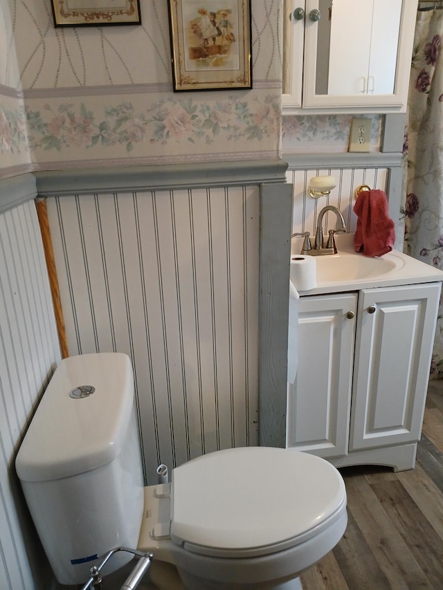 bathroom featuring wood finished floors, vanity, toilet, and wallpapered walls