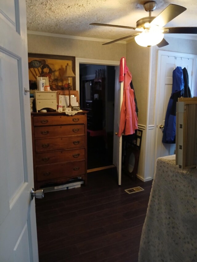 bedroom featuring visible vents, a ceiling fan, dark wood-style floors, ornamental molding, and a textured ceiling