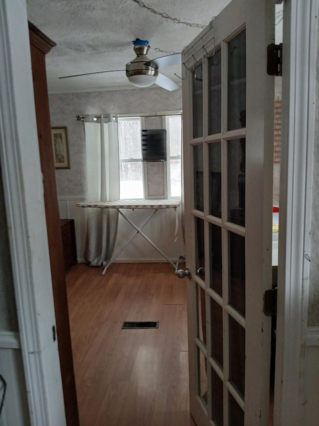 hallway featuring a textured ceiling, visible vents, and wood finished floors