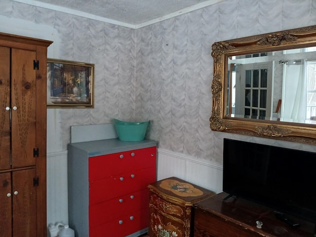 interior space with wainscoting, a textured ceiling, and wallpapered walls