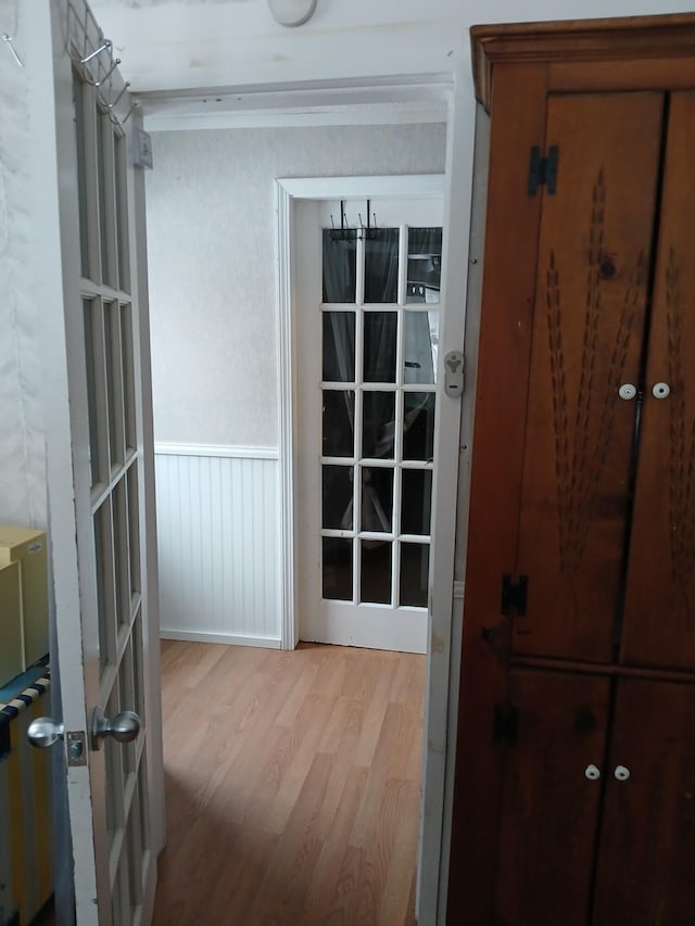 hall featuring ornamental molding, a wainscoted wall, and wood finished floors