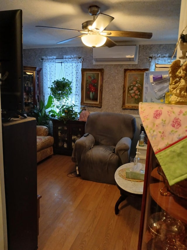 living room featuring ceiling fan, a wall unit AC, and wood finished floors