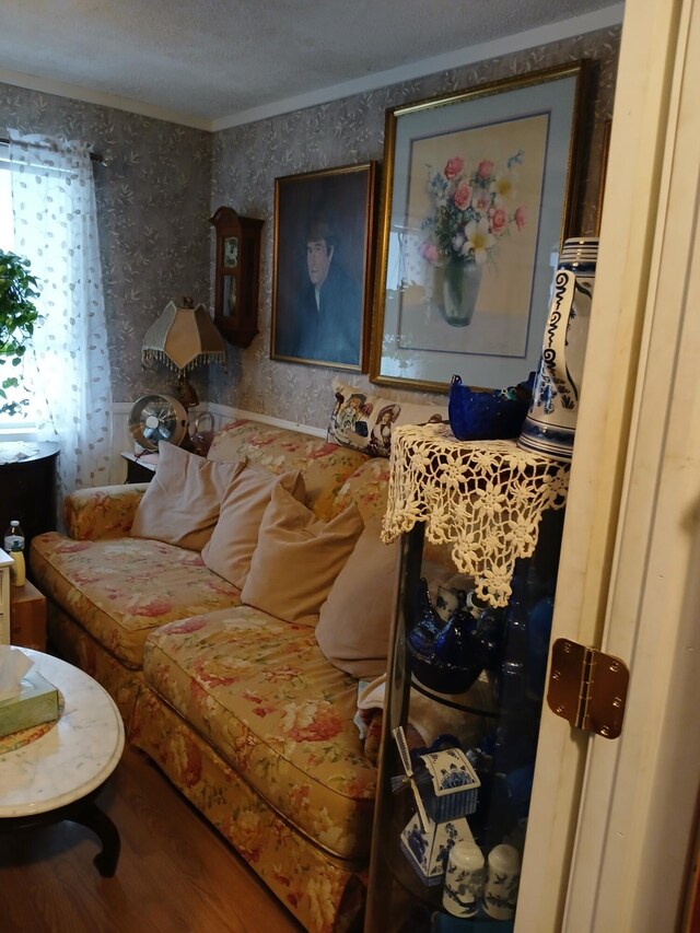 living area with wallpapered walls, crown molding, and wood finished floors