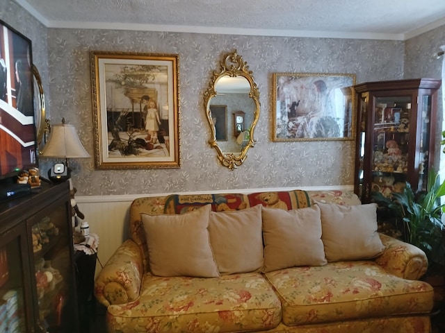 living area with wainscoting, a textured ceiling, and wallpapered walls