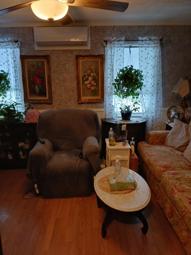 sitting room featuring ceiling fan, a wall mounted AC, and wood finished floors