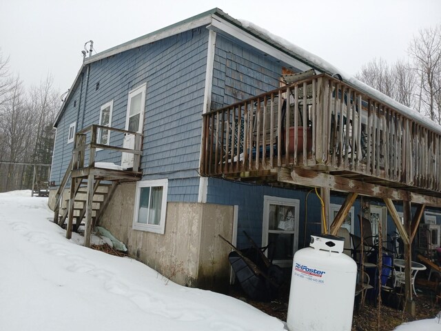 snow covered back of property with stairs