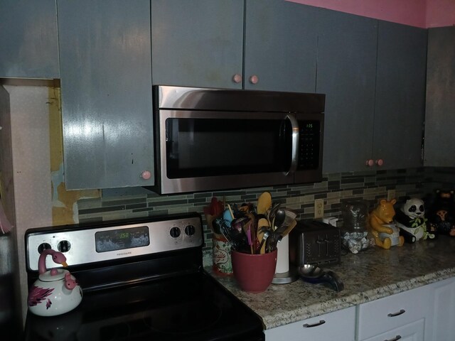 kitchen with appliances with stainless steel finishes, backsplash, and light stone countertops