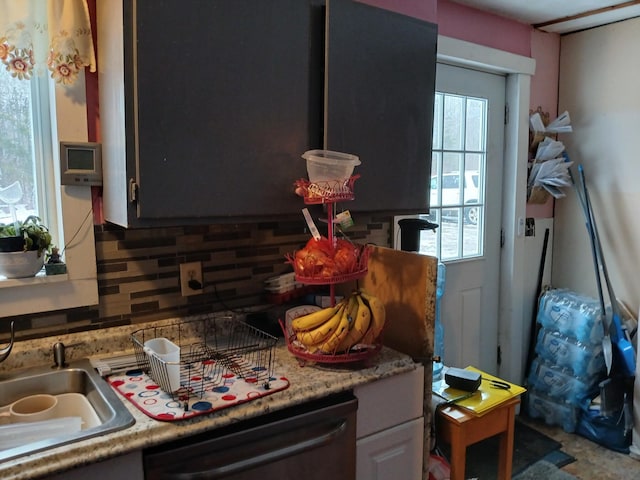 interior space with tasteful backsplash, light countertops, dishwasher, and a sink