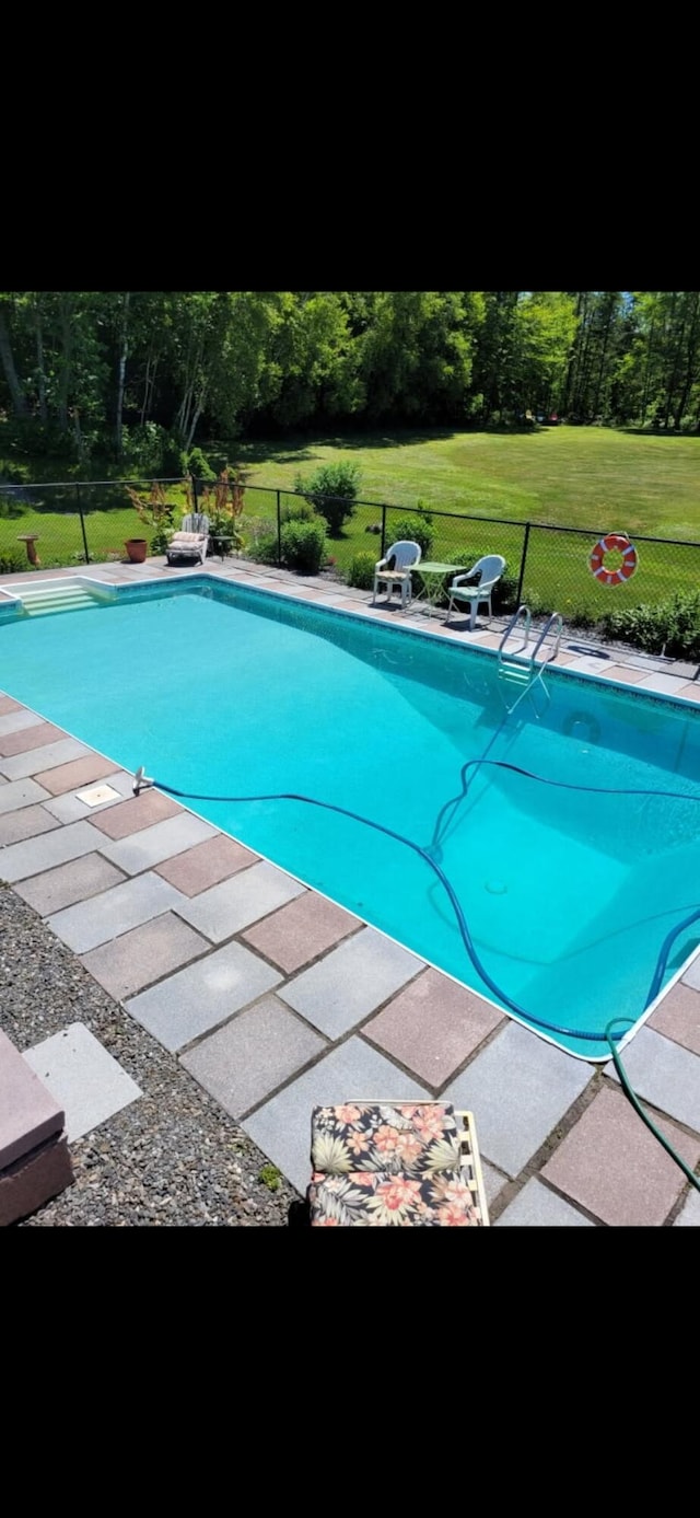 outdoor pool with fence and a lawn