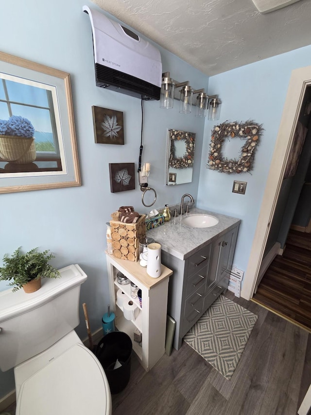 bathroom featuring toilet, a textured ceiling, wood finished floors, and vanity