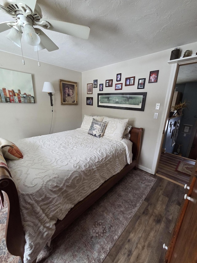 bedroom with ceiling fan, a textured ceiling, baseboards, and wood finished floors