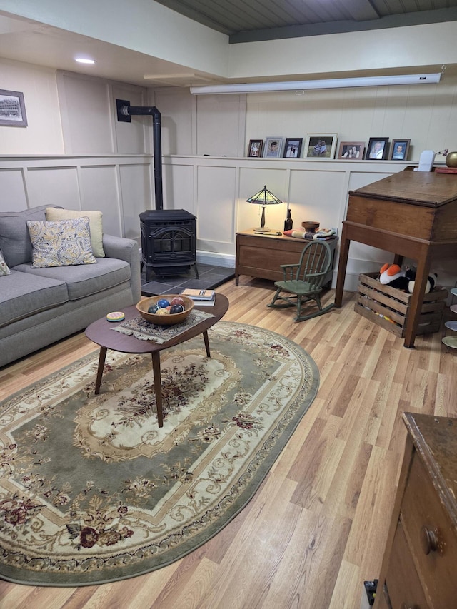 living area featuring light wood finished floors, a wood stove, and a decorative wall