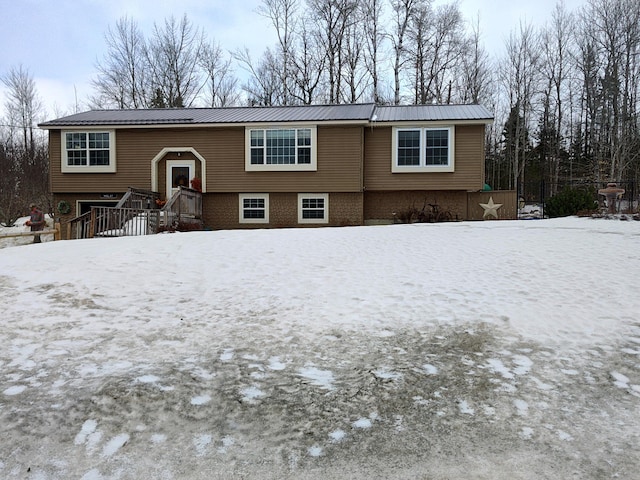 bi-level home featuring brick siding and metal roof