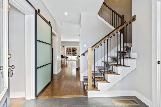 foyer entrance with hardwood / wood-style floors, stairway, visible vents, baseboards, and a barn door