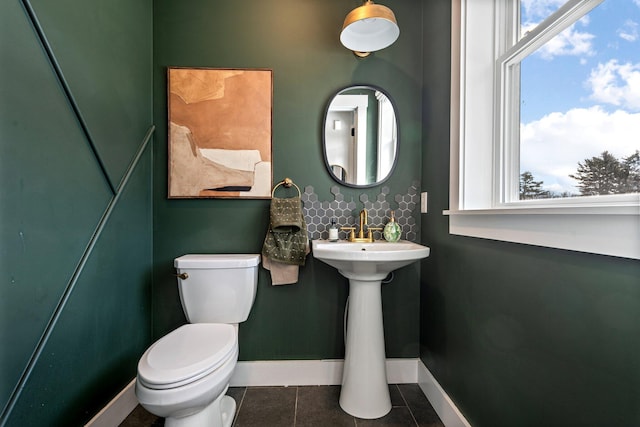 half bathroom with tile patterned flooring, toilet, and baseboards