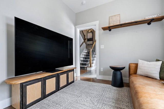 living room with stairs, wood finished floors, and baseboards