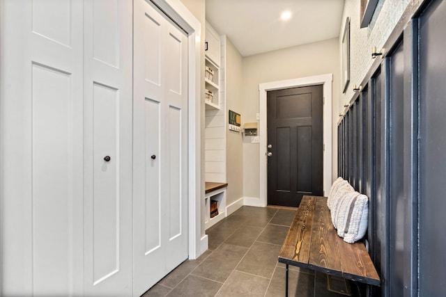 mudroom featuring dark tile patterned flooring and baseboards