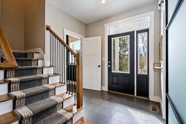 foyer with visible vents, baseboards, tile patterned flooring, and stairway