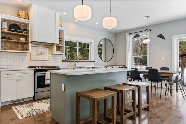 kitchen featuring open shelves, gas range, tasteful backsplash, and a healthy amount of sunlight