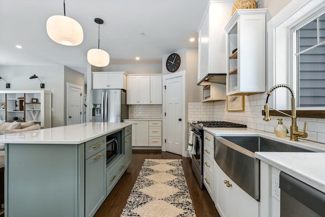 kitchen with a sink, stainless steel appliances, light countertops, white cabinets, and dark wood-type flooring