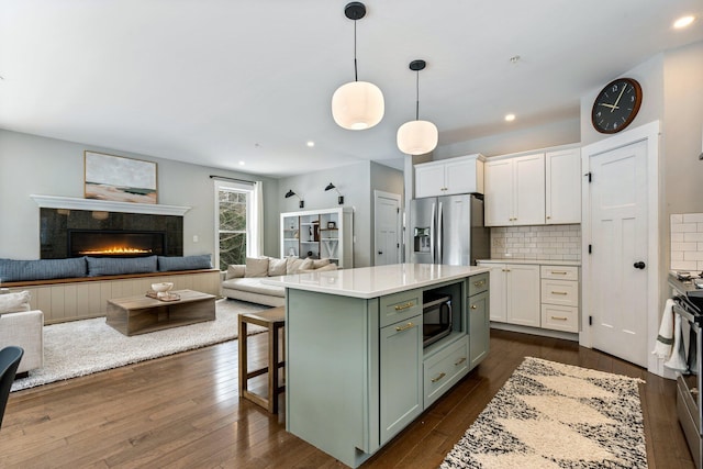 kitchen with white cabinets, stainless steel fridge with ice dispenser, black microwave, and green cabinetry