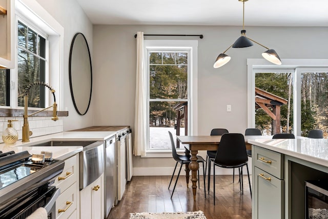 kitchen featuring gas range, a healthy amount of sunlight, dark wood-style flooring, and light countertops